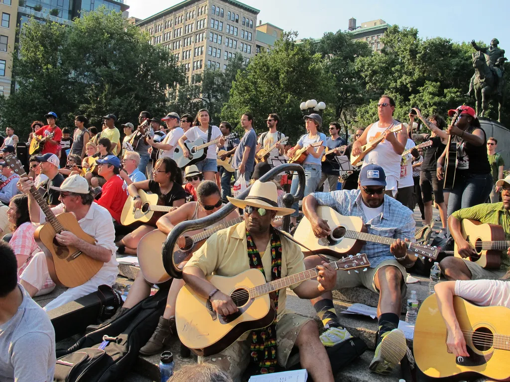 A large group of guitarists playing together in a city park on Make Music Day.